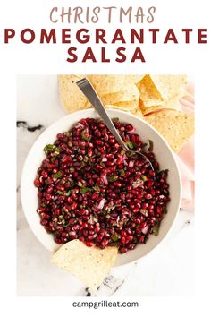 a white bowl filled with pomegranate salsa next to tortilla chips