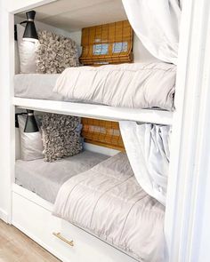 two bunk beds with white sheets and pillows