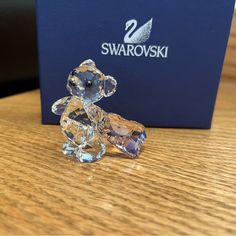 a crystal teddy bear sitting on top of a wooden table next to a blue box