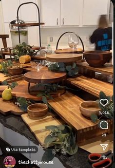 a kitchen counter with wooden cutting boards and bowls on it, surrounded by greenery