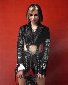 a woman in black leather outfit with chains on her waist and leg, posing for the camera