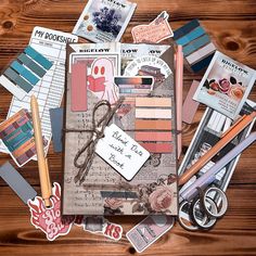 the contents of a scrapbook laid out on top of a wooden table with paper and stickers