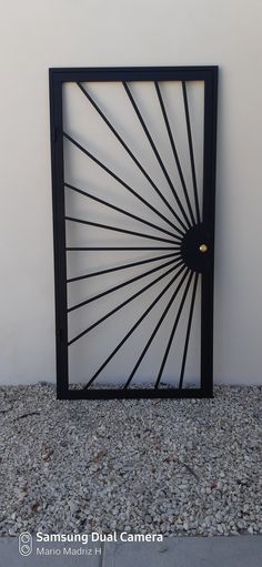 a black gate with an intricate design on the front and back sides, against a white wall