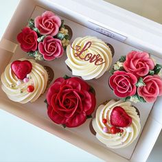 four cupcakes in a box decorated with roses