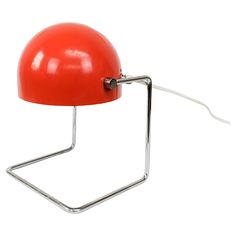 a red table lamp with a metal base and a light bulb attached to the back of it