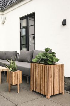 two wooden planters sitting next to each other near a couch and table on the sidewalk