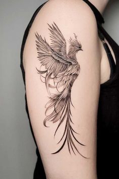 a woman's arm with a black and white bird tattoo on the left shoulder