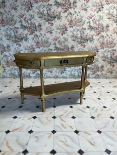 a small wooden table sitting on top of a tiled floor next to a floral wall