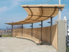 a wooden bench sitting on top of a cement floor next to a fence and street light