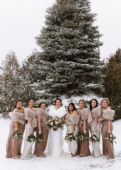 a group of women standing next to each other in front of a snow covered tree