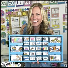 a woman holding up a blue tray with lots of different items on it in front of a bulletin board