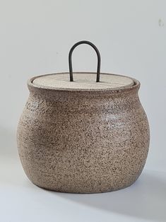 a brown pot with a black handle sitting on a white surface