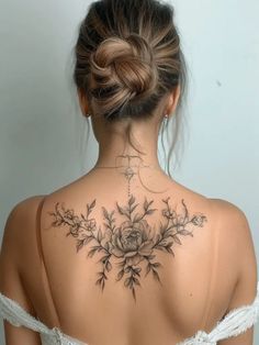 the back of a woman's neck with flowers on it and leaves in the middle