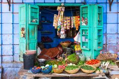 an open door with many vegetables and fruits on it in front of a blue building