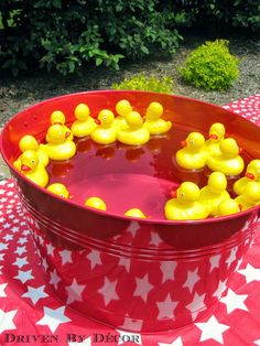 a red bucket filled with yellow rubber ducks on top of a checkered table cloth