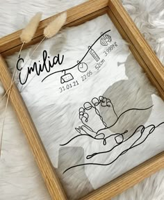 a wooden frame with a drawing on it and a feather in the middle next to it