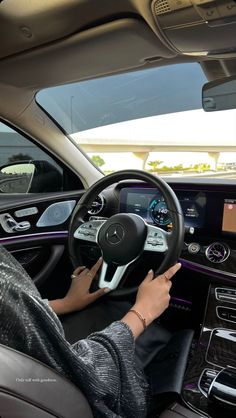 a woman driving a car with her hands on the steering wheel