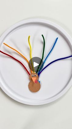 a paper plate with a turkey made out of yarn and colored cords on top of it