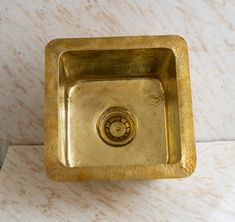 a gold sink in a bathroom next to a white marble counter top with a black faucet