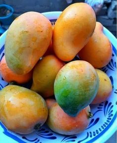 a blue and white bowl filled with mangoes