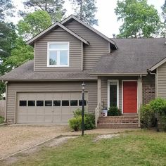 a gray house with a red door in the front yard