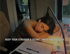 a woman sleeping on top of a desk next to an open notebook with writing on it