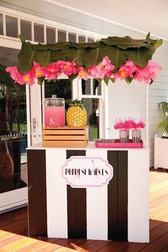 an outdoor bar with pink flowers and pineapples