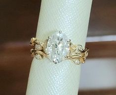 a fancy ring with an oval cut diamond in the center and leaves on each band