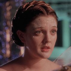 a woman wearing a tiara and looking off into the distance with lights in the background