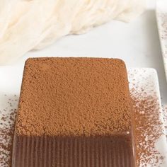 a piece of chocolate cake sitting on top of a white plate with powdered sugar