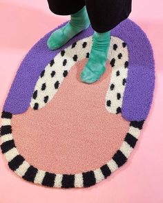 a person standing on top of a pink rug with black and white circles around it