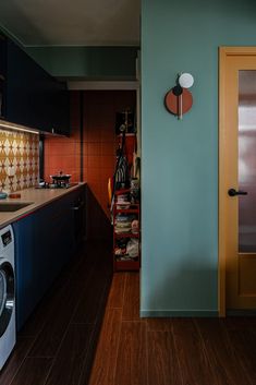 a washer and dryer in a small room with blue walls, wood flooring and cabinets