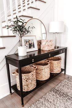 a foyer table with baskets under the stairs