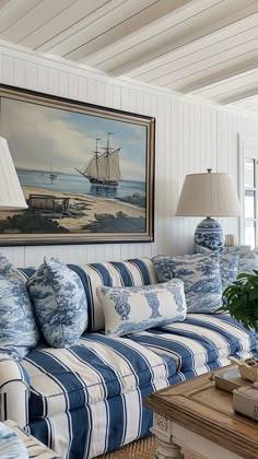 a blue and white striped couch in a living room next to a painting on the wall