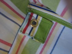 a close up view of a green and white striped shirt with a gold button on it