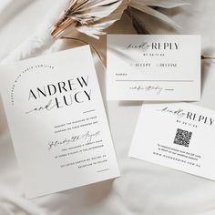 the wedding stationery is laid out on top of the white bed sheets and flowers