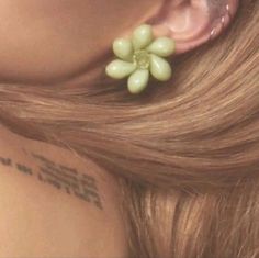 a close up of a person's ear with grapes attached to the back of her ear