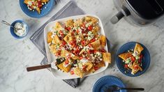 a platter filled with nachos and salsa next to two plates of chips