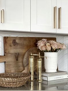 a kitchen counter with flowers in a vase and books on the shelf next to it