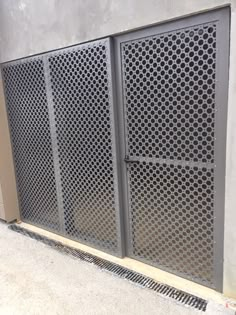 a metal gate on the side of a building next to a wall with holes in it