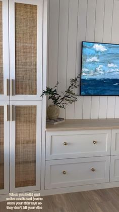 a painting hangs on the wall next to some white cabinets