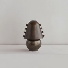 a large metal vase sitting on top of a white table