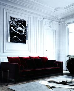 a living room with white walls and red couches in front of a painting on the wall