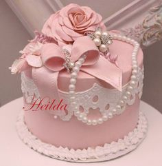 a pink cake with pearls and a rose on top