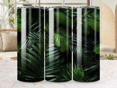 three glass tumblers with green leaves on them sitting on a marble countertop in front of a couch