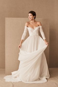 a woman in a white wedding dress posing for the camera with her arms around her waist