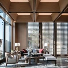 a living room filled with lots of furniture next to large glass windows covered in wooden slats