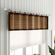 a bamboo blind hanging from the side of a window in a room with white walls