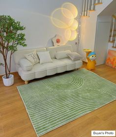 a white couch sitting on top of a hard wood floor next to a green rug