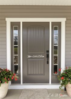 a gray front door with two potted plants